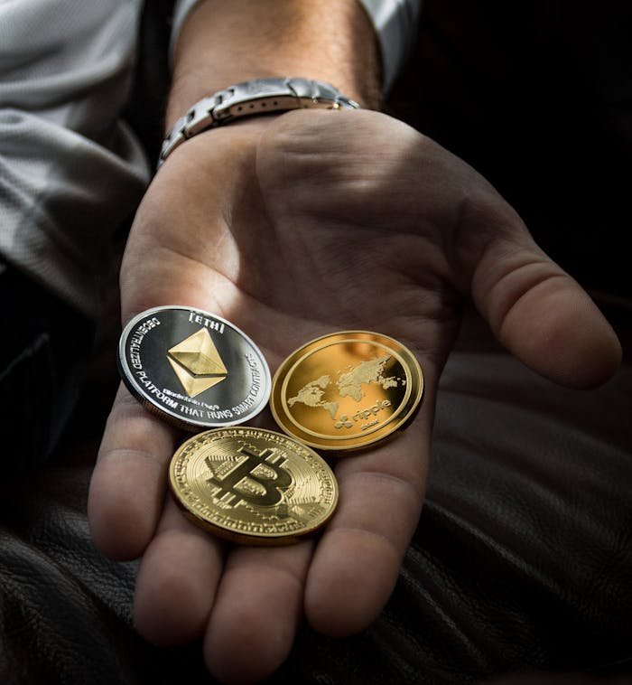 about-us Hand holding Bitcoin, Ethereum, and Ripple coins representing digital currency.